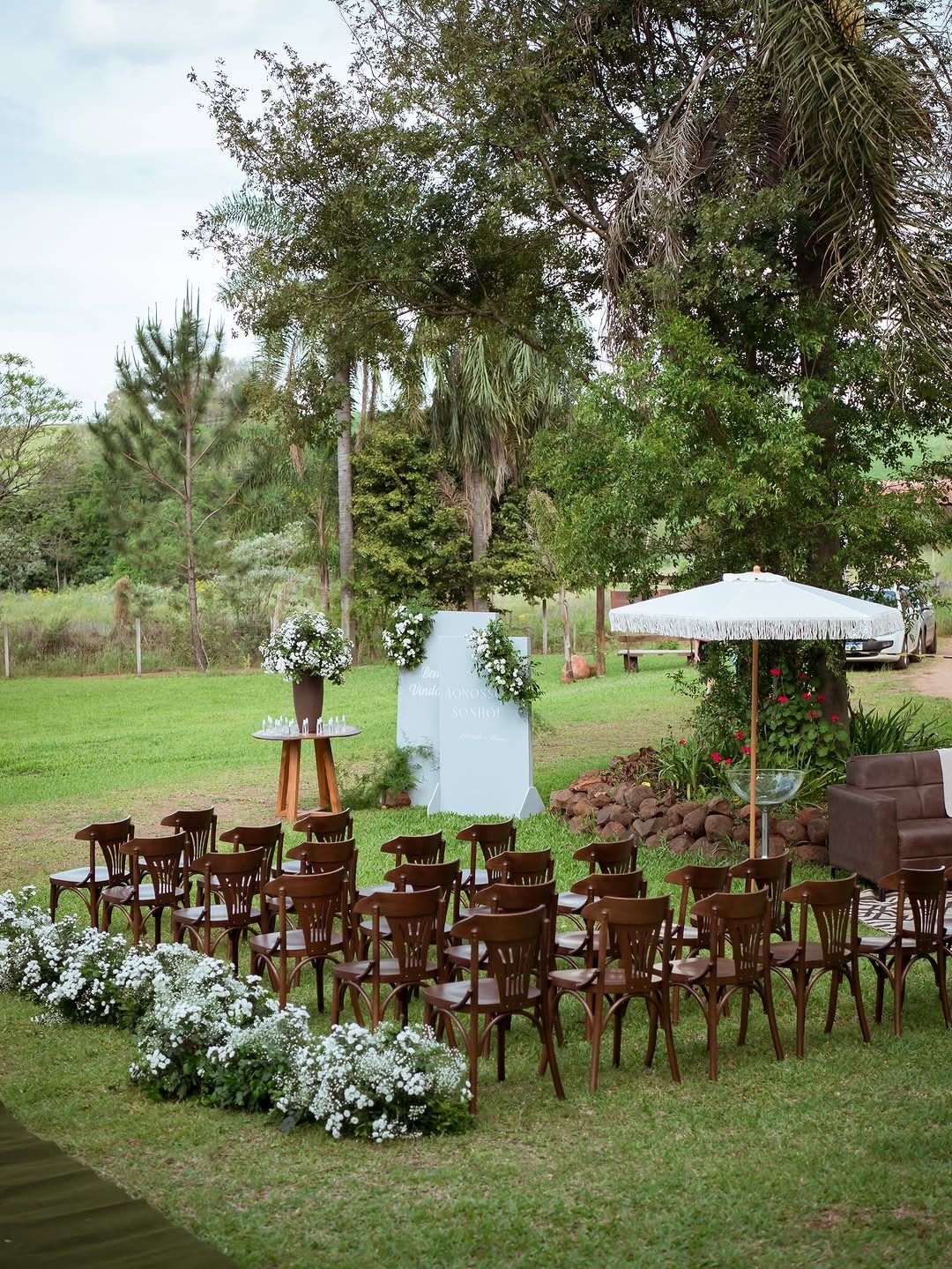 Cadeiras de madeira e flores brancas organizadas para casamento ao ar livre