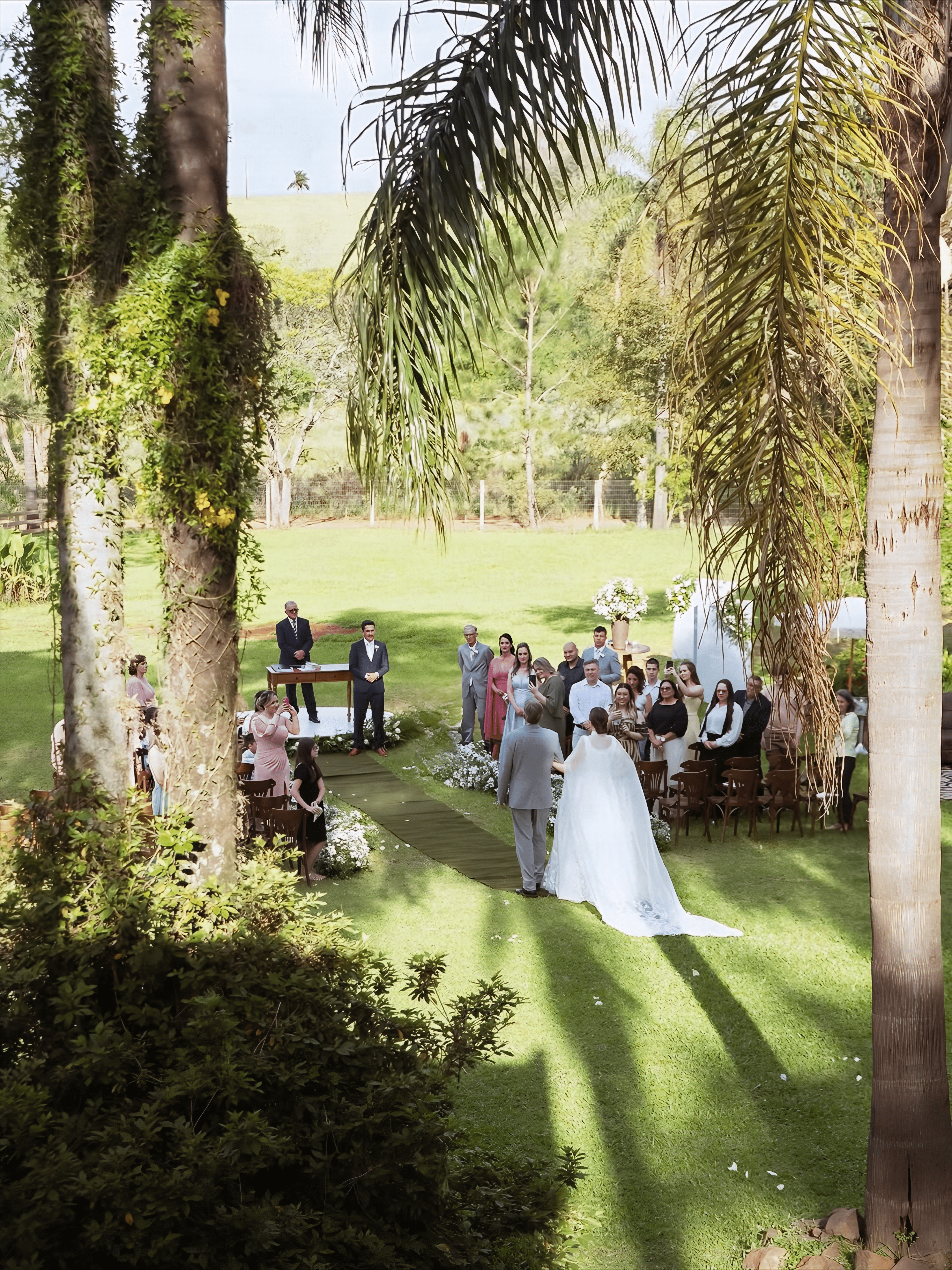 Cerimônia de casamento vista do alto entre os coqueiros e o gramado do Recanto
