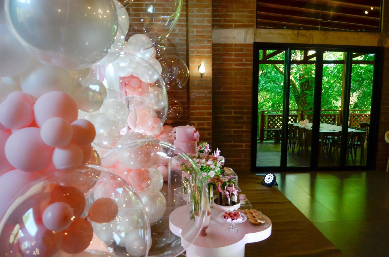 Salão de eventos decorado com balões e vista para o jardim