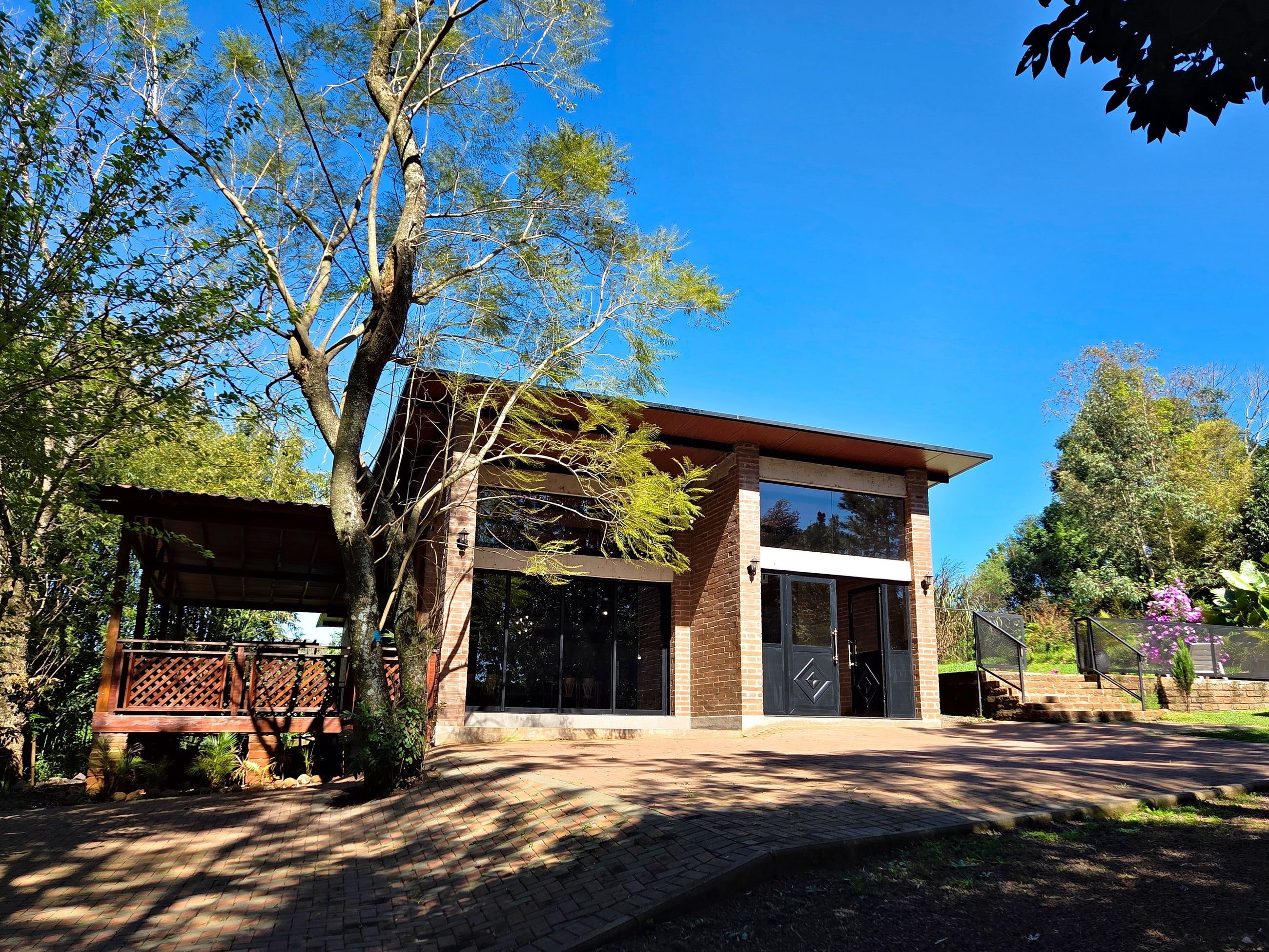Fachada do salão de eventos com tijolos aparentes e árvores ao redor
